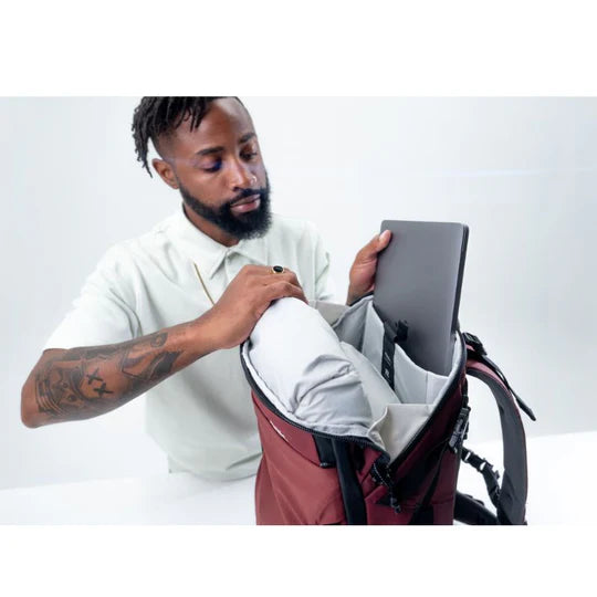 Matador GlobeRider35 Travel Backpack - Garnet man putting laptop computer in sleeve compartment inside bag